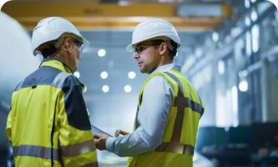 Two men in hard hats talking in an industrial setting