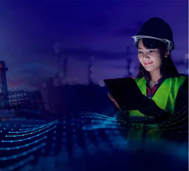 A woman in a hard hat and safety vest holding a tablet computer