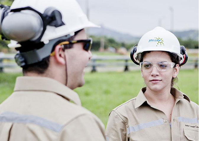Two people wearing hard hats talking to each other