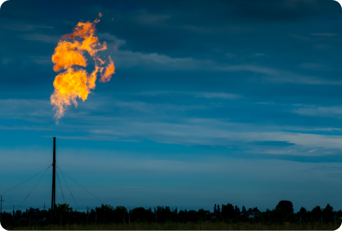 A gas flare illuminates the night sky, casting a bright glow against the dark night sky