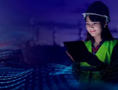 A woman in a hard hat and safety vest holding a tablet computer