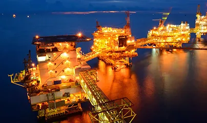 Large offshore oil rigs at night with lights on