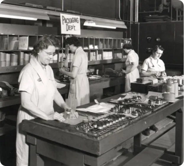 Women working in a factory with a large table