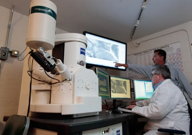 Two men in white lab coats looking at a computer screen