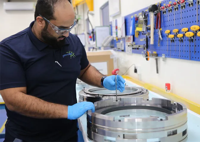 A man in blue shirt and gloves working on a machine