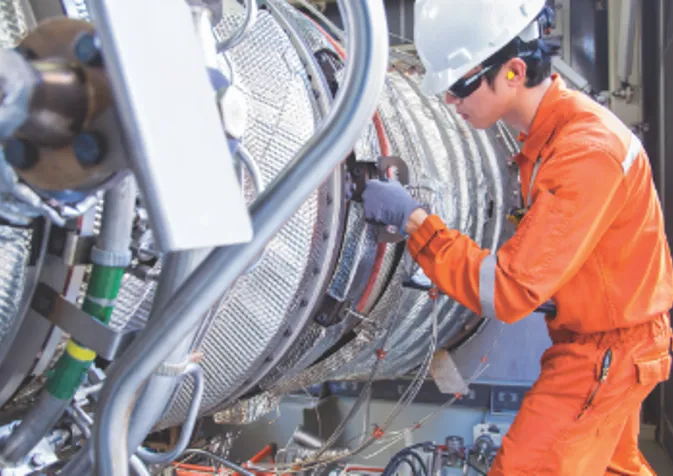 A man in an orange uniform working on a large machine