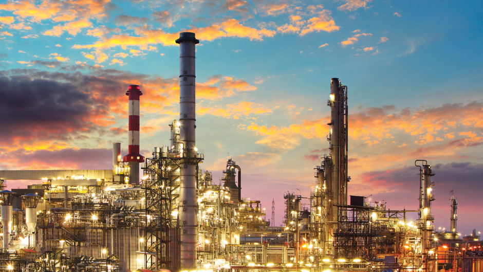 A refinery at sunset with a cloudy sky