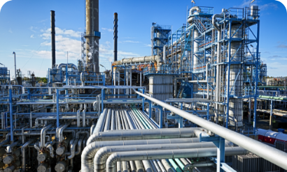An industrial facility with an intricate network of pipes set against a bright blue sky