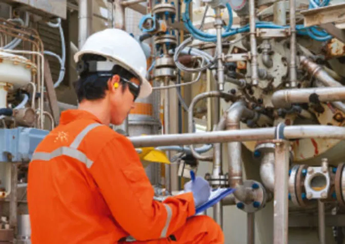 A man in an orange uniform is working on a pipe