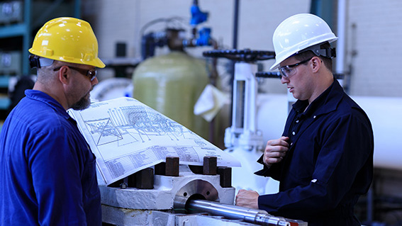 Two men in hard hats looking at a blueprint