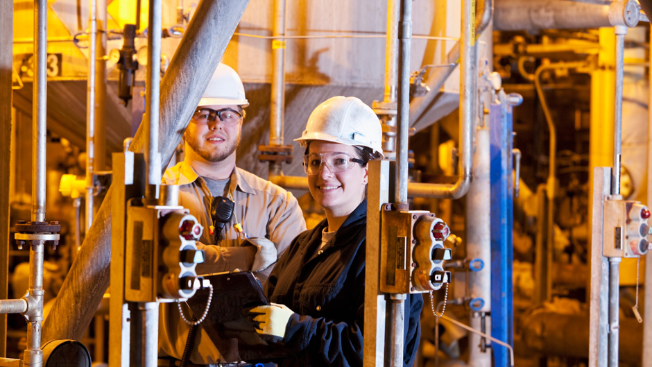 Two people in hard hats standing in front of a large industrial machine